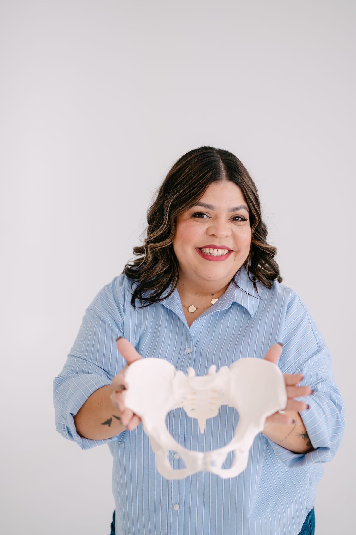 Melanie smiling and holding out a model of the pelvis