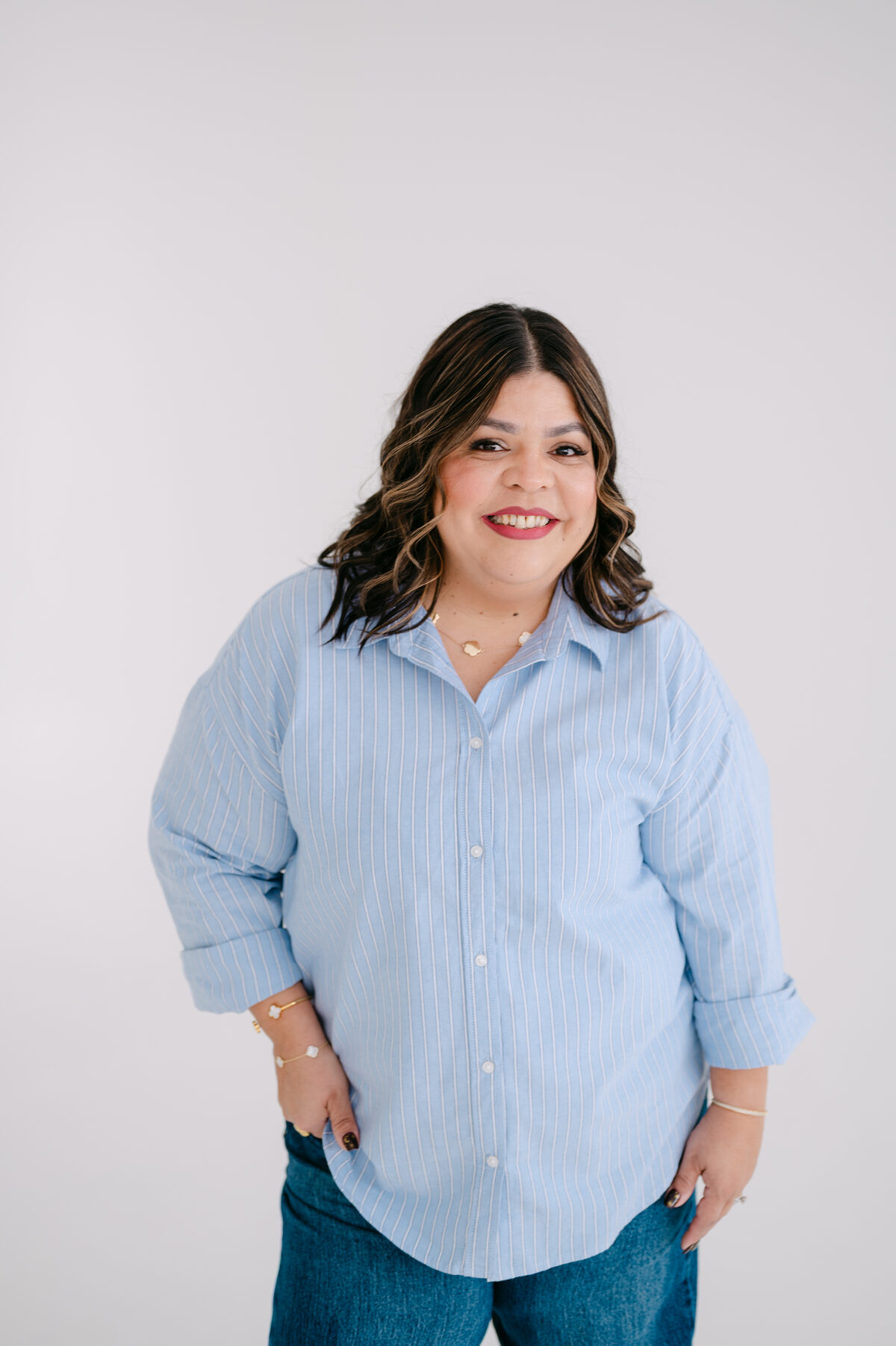 Melanie smiling, standing in a blue striped shirt